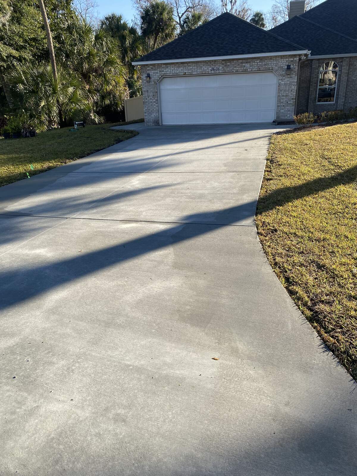 Finished concrete driveway leading to a brick home garage